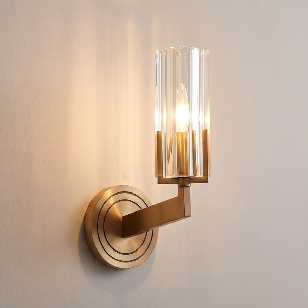 Verona ribbed glass wall light on a brass arm, lit against plaster