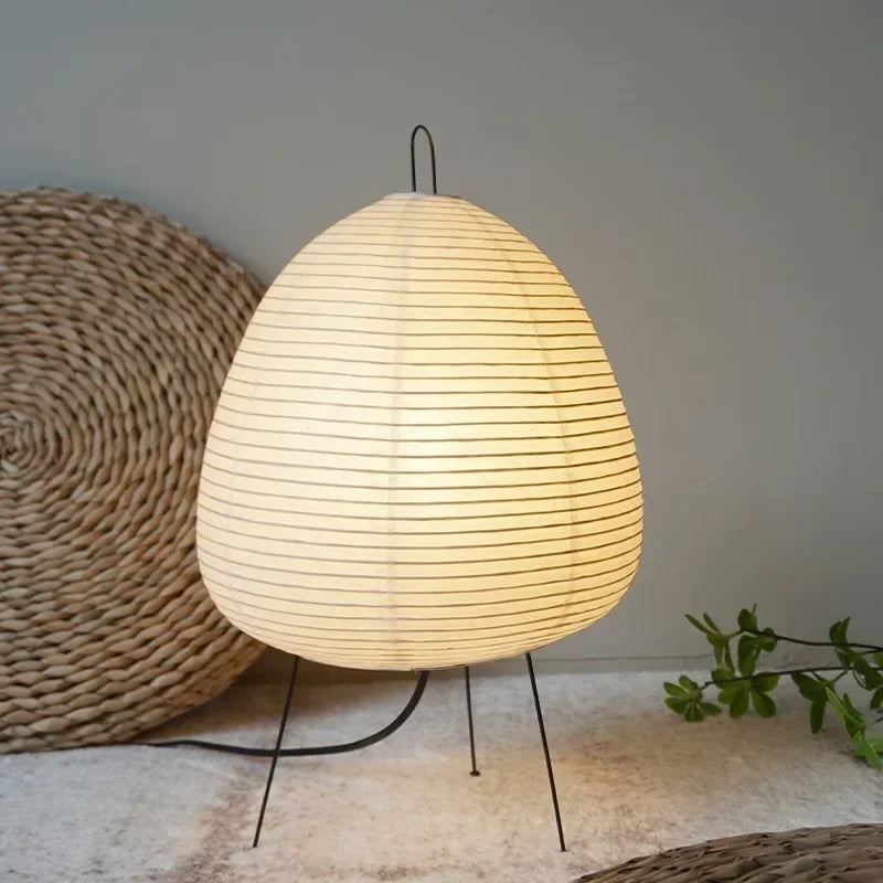 Gifu rice paper table lamp lit on a low shelf beside a woven seat