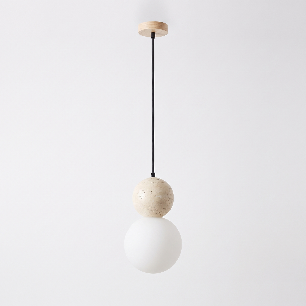 Siena travertine pendant light, a stone sphere above a frosted opal glass globe on a black cord, on a plain white background