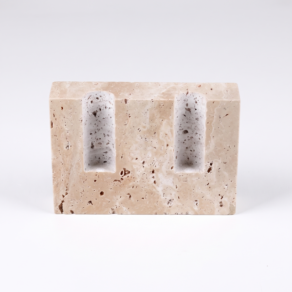 Tivoli travertine candle holder, a solid unpolished stone block with two carved taper wells, on a plain white background