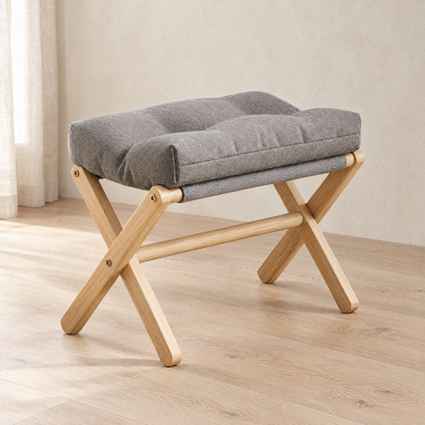 Kiso X frame footstool with a grey padded cushion on a pale oak floor