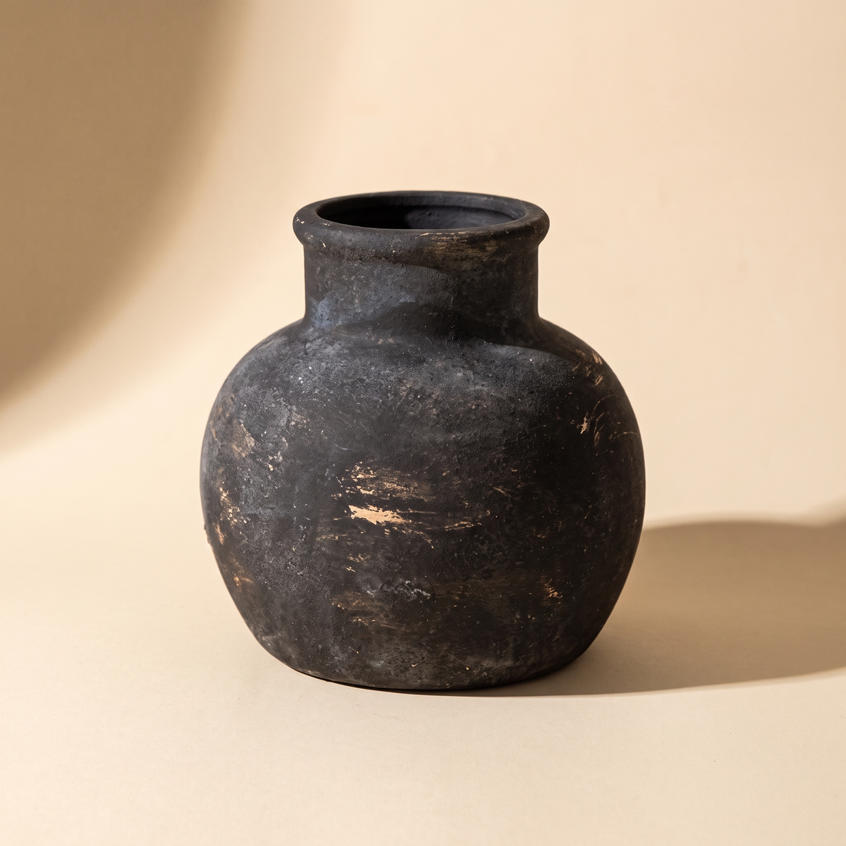 Mashiko rustic ceramic jar vase in charcoal with worn pale marks, on a cream backdrop