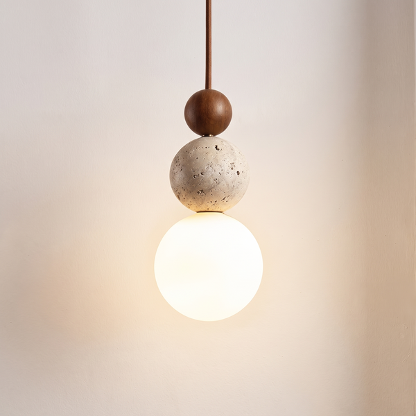 Portofino pendant light with a walnut ball, a travertine ball and a glowing opal glass globe against a limewash wall