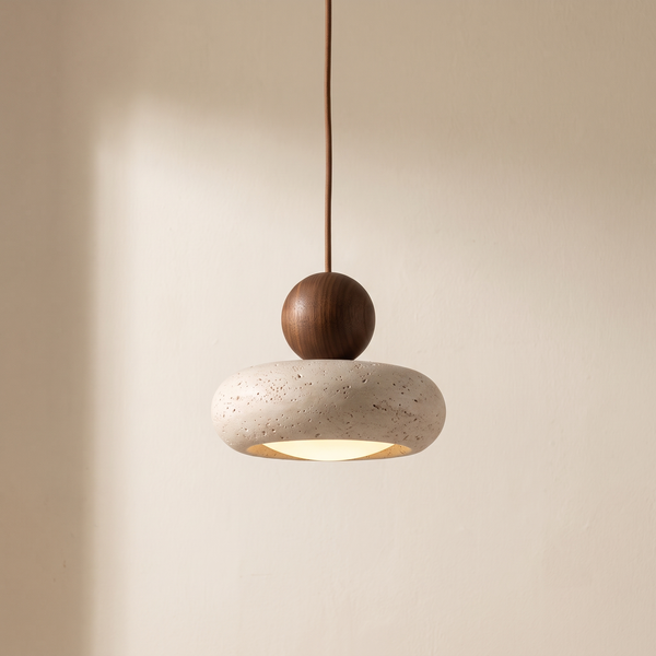 Ravello travertine pendant with a walnut tone ball, lit against a cream plaster wall